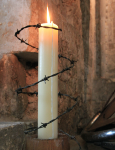 Candle alight with barbed wire wrapped around